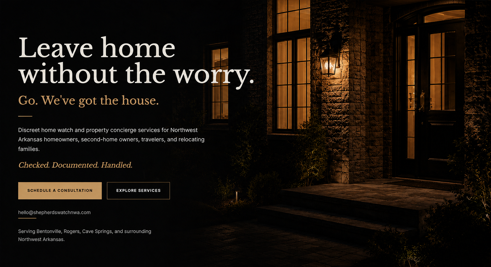 Warmly lit stone estate entry at night with porch lights and landscape lighting.